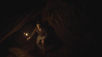 homem segurando uma queimando luz da tocha explorando floresta caverna panorama dentro Sombrio noite video