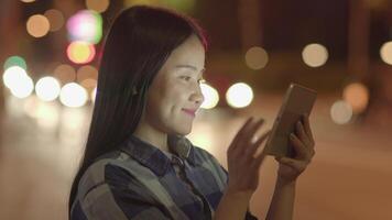 giovane asiatico donna utilizzando inteligente Telefono tavoletta nel il città strade video