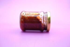 chili sauce in a glass bottle. chili sauce isolated on a purple background. photo