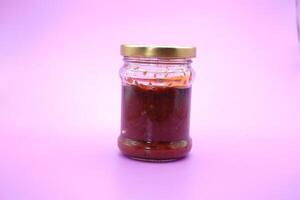 chili sauce in a glass bottle. chili sauce isolated on a purple background. photo