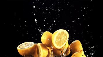 metà di limoni volare su e autunno giù con spruzzi di acqua. su un' nero sfondo. girato su un' alta velocità telecamera a 1000 fps. video