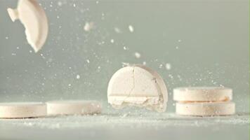 The pill falls on the table and splits into pieces. On a white background. Filmed on a high-speed camera at 1000 fps. video