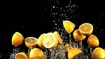 Pieces of juicy lemons with splashes of water fly up and fall down. On a black background. Filmed is slow motion 1000 fps. video