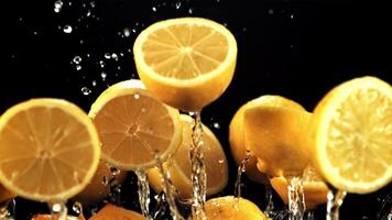 Halves of lemons fly up and fall down with splashes of water. On a black background. Filmed on a high-speed camera at 1000 fps. video