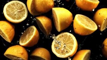 Halves of fresh lemons with drops of water fly up and rotate in flight. On a black background. Filmed on a high-speed camera at 1000 fps. video