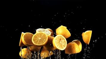 Halves of fresh lemons with drops of water fly up and rotate in flight. On a black background. Filmed on a high-speed camera at 1000 fps. video