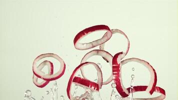 Rings of red onion with drops of water fly up and rotate in flight. On a white background. Filmed on a high-speed camera at 1000 fps. video