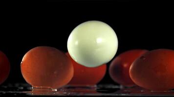 The egg falls on the table with splashes of water. On a black background. Filmed on a high-speed camera at 1000 fps. video