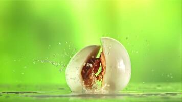 The egg falls and splits into pieces. On a green background. Filmed is slow motion 1000 fps. video