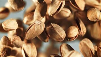 A pile of pistachios rises up and falls down. On a blue background. Filmed on a high-speed camera at 1000 fps. video