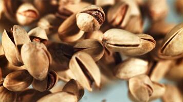 A pile of pistachios rises up and falls down. On a blue background. Filmed on a high-speed camera at 1000 fps. video