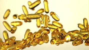 Omega 3 vitamin capsules rise and fall. On a gray background. Filmed is slow motion 1000 fps. video