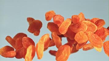 Dried apricots rise up and fall down. On a blue background. Filmed is slow motion 1000 fps. video