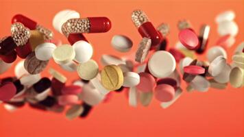 Different types of pills fly up and fall down. On a red background. Filmed on a high-speed camera at 1000 fps. video