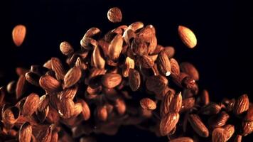 Almonds go up and fall. On a black background. Filmed is slow motion 1000 fps. video