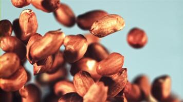 Peanuts rise up and fall down. On a blue background. Filmed on a high-speed camera at 1000 fps. video