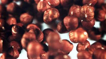 Peeled hazelnuts rise up and rotate in flight. On a blue background. Filmed is slow motion 1000 fps. video