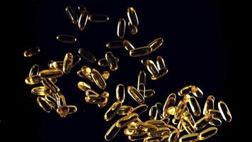 Omega 3 vitamin capsules soar up and fall down. On a black background. Filmed on a high-speed camera at 1000 fps. video
