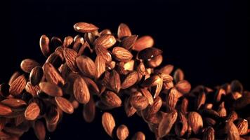 Almonds go up and fall. On a black background. Filmed is slow motion 1000 fps. video