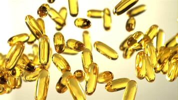 Omega 3 vitamin capsules soar up and fall. On a gray background. Filmed is slow motion 1000 fps. video