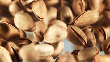 A pile of pistachios rises up and falls down. On a blue background. Filmed on a high-speed camera at 1000 fps. video