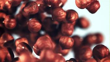 Peeled hazelnuts rise up and rotate in flight. On a blue background. Filmed is slow motion 1000 fps. video