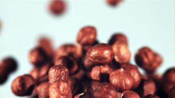 Peeled hazelnuts rise up and rotate in flight. On a blue background. Filmed is slow motion 1000 fps. video