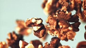 Peeled walnuts rise up and fall. On a blue background. Filmed is slow motion 1000 fps. video