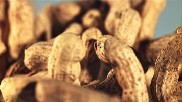 Peanuts in the shell fly up and fall down. On a blue background. Filmed is slow motion 1000 fps. video