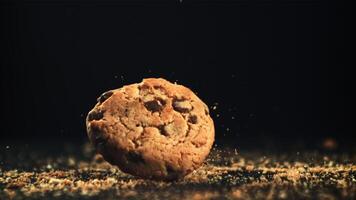 Cookies with pieces of chocolate fall on the table. On a black background. Filmed on a high-speed camera at 1000 fps. High quality FullHD footage video