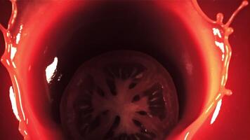 un' pezzo di pomodoro con spruzzi cascate in il pomodoro succo. superiore vedere.filmato su un' alta velocità telecamera a 1000 fps. alto qualità FullHD metraggio video