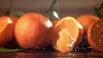 Slices of fresh tangerines fall on a wooden table. Filmed on a high-speed camera at 1000 fps. High quality FullHD footage video