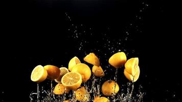 Pieces of lemon with drops of water fly up and fall. On a black background. Filmed on a high-speed camera at 1000 fps. video