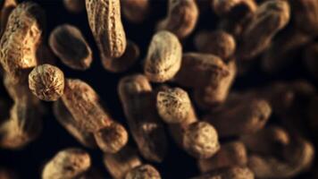 Peanuts in the shell fly up and rotate in flight. On a black background. Top view. Filmed is slow motion 1000 fps. video