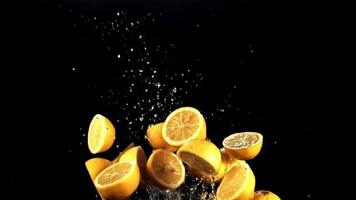 Pieces of lemon with drops of water fly up and fall on the table. On a black background. Filmed on a high-speed camera at 1000 fps. video