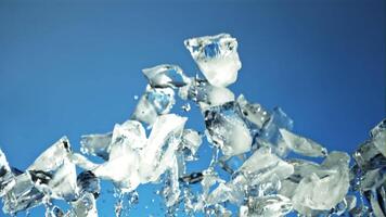 Pieces of ice with splashes of water soar up and fall. On a blue background. Filmed is slow motion 1000 fps. video