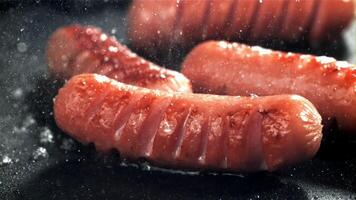 Sausages are fried with splashes in a pan. Filmed on a high-speed camera at 1000 fps. High quality FullHD footage video