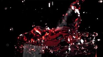 rood wijn gieten in een glas Aan een zwart achtergrond. gefilmd Aan een hoge snelheid camera Bij 1000 fps. hoog kwaliteit full HD beeldmateriaal video
