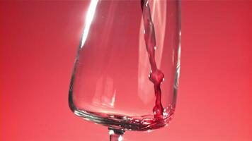 rood wijn is gegoten in een glas. Aan een roze achtergrond. gefilmd Aan een hoge snelheid camera Bij 1000 fps. hoog kwaliteit full HD beeldmateriaal video