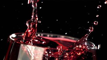 une laissez tomber chutes dans une verre de du vin. sur une noir Contexte. filmé sur une haute vitesse caméra à 1000 ips. haute qualité Full HD métrage video