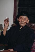 retrato de un mayor asiático hombre de fumar un cigarrillo. foto