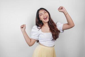 A happy young Asian woman wearing casual wear is posing to the camera with her hands open, expressing freedom and carefree photo