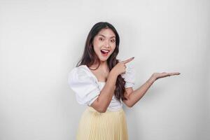 A cheerful Asian woman is pointing copy space beside her, isolated by white background. photo