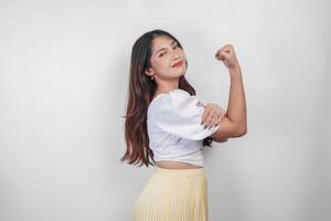 A portrait of Asian woman showing strong gesture by lifting her arms and muscles smiling proudly. photo