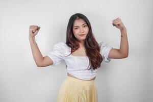 A portrait of Asian woman showing strong gesture by lifting her arms and muscles smiling proudly. photo