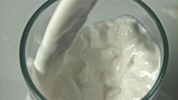 Fresh milk is poured into a glass on a white background. Filmed on a high-speed camera at 1000 fps. High quality FullHD footage video