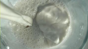 The milk is poured into a glass with splashes. Top view. Filmed on a high-speed camera at 1000 fps. High quality FullHD footage video