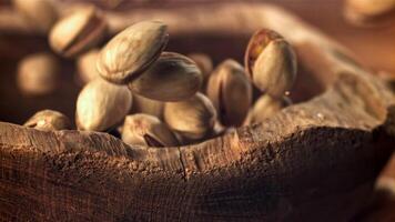 Pistachios fall into a wooden bowl. Filmed on a high-speed camera at 1000 fps. High quality FullHD footage video