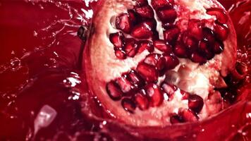 Part of the pomegranate falls into the juice with splashes. Filmed on a high-speed camera at 1000 fps. High quality FullHD footage video