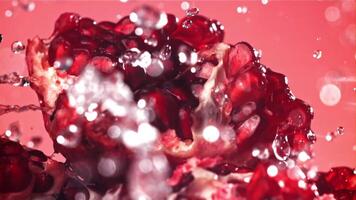 Splashed water pours onto fresh pomegranates. Filmed on a high-speed camera at 1000 fps. High quality FullHD footage video